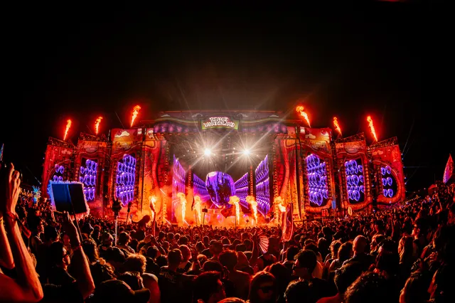 The Beyond Wonderland main stage at the Gorge after dark, flame jets firing along the top of a red and purple proscenium, the crowd silhouetted in front of it.